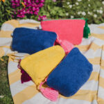 Pochette de voyage EIDA avec motif wax vibrant, fermeture éclair flashy et pompon artisanal marocain